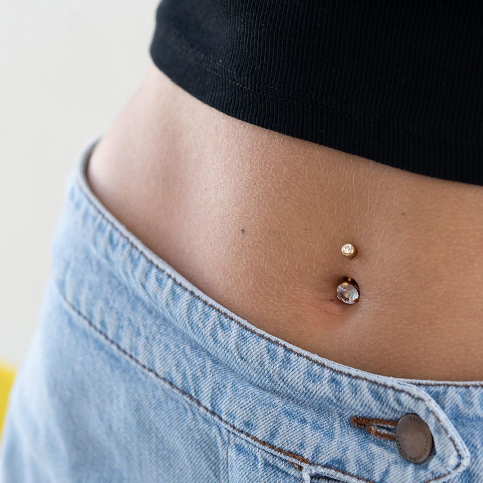 Vergoldetes Bauchnabelpiercing mit einem großen Stein