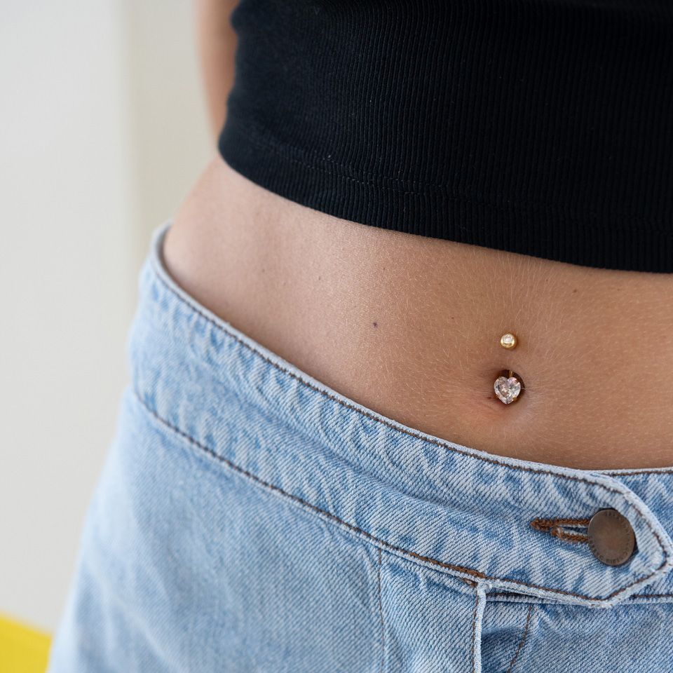 Bauchnabelpiercing in verschiedenen Farben mit Herzstein
